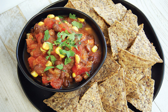 corn and black bean salsa in bowl surrounded by whole-grain crackers