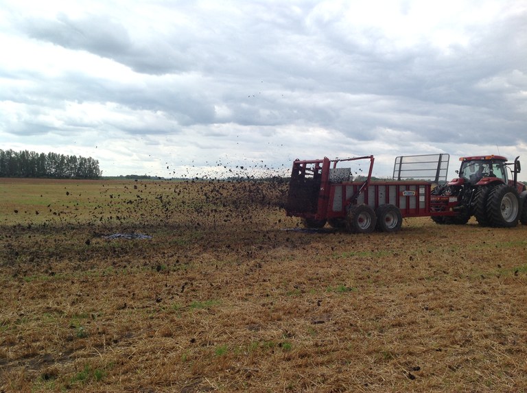 a tractor applying manure over plastic sheets