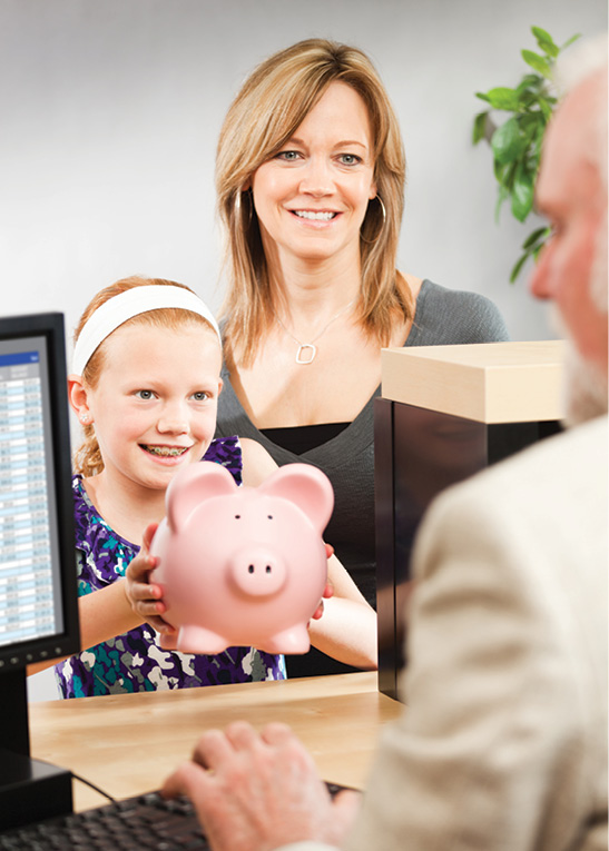 mom and daughter with piggy bank at a bank teller's window