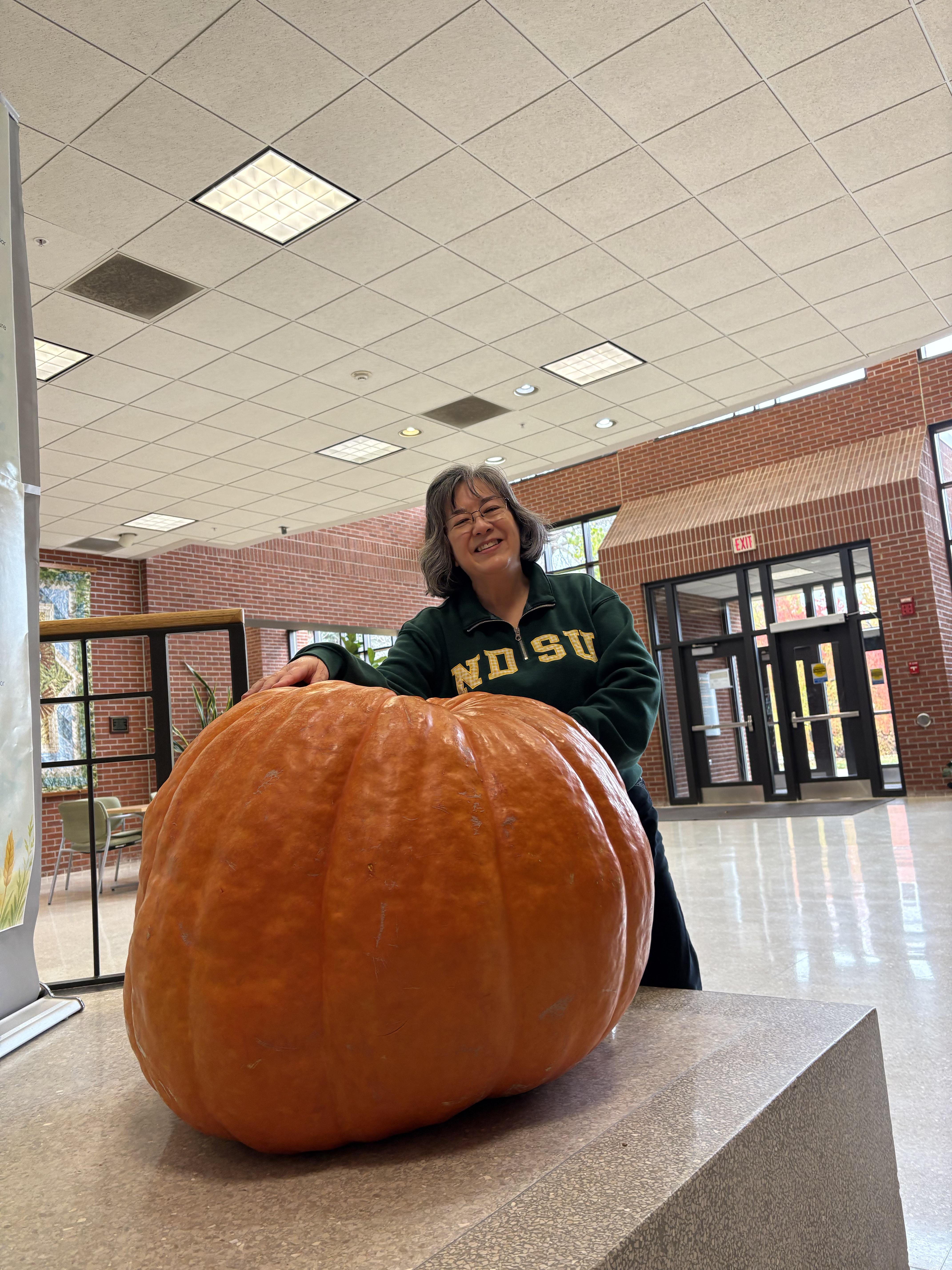 Esther McGinnis, NDSU Extension horticulturist, stands next to a giant pumpkin on the NDSU campus, and shares some little-known facts about pumpkin in this week's Dakota Gardener. (NDSU photo)