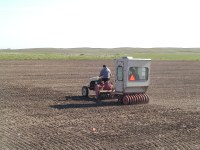 Central Grasslands researchers seed plots for a study of perennial grasses as a source of biomass for biofuels. Center Director Paul Nyren drives the tractor while research technician Mark Erickson rides in the drill.