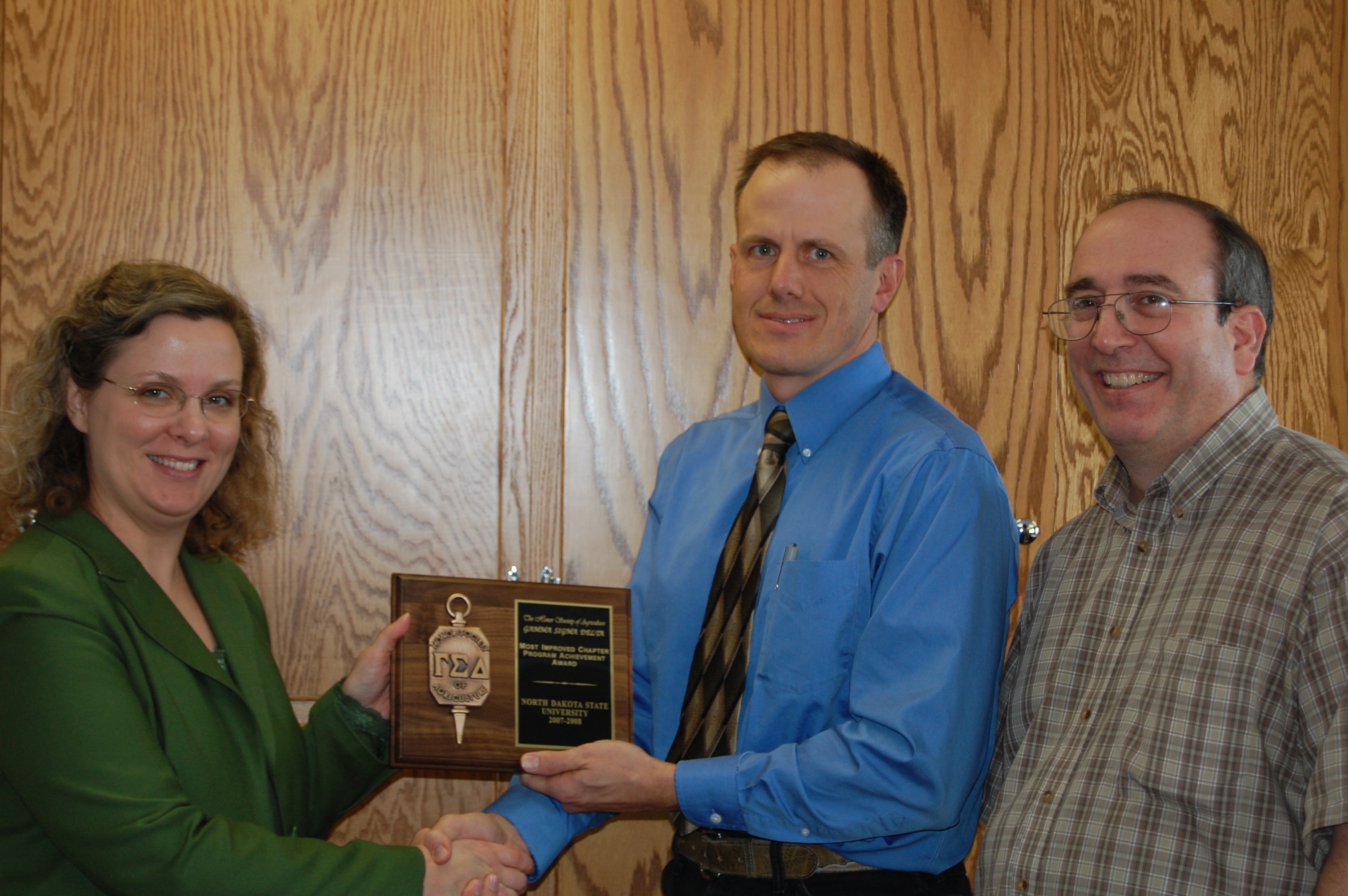 Charlene Wolf-Hall, an associate professor of food microbiology at NDSU and president-elect of Gamma Sigma Delta International, presents a plaque to Greg Lardy, (center) president of NDSU's Gamma Sigma Delta chapter, and Frank Manthey, past chapter president. NDSU's Gamma Sigma Delta was named the most improved chapter.
