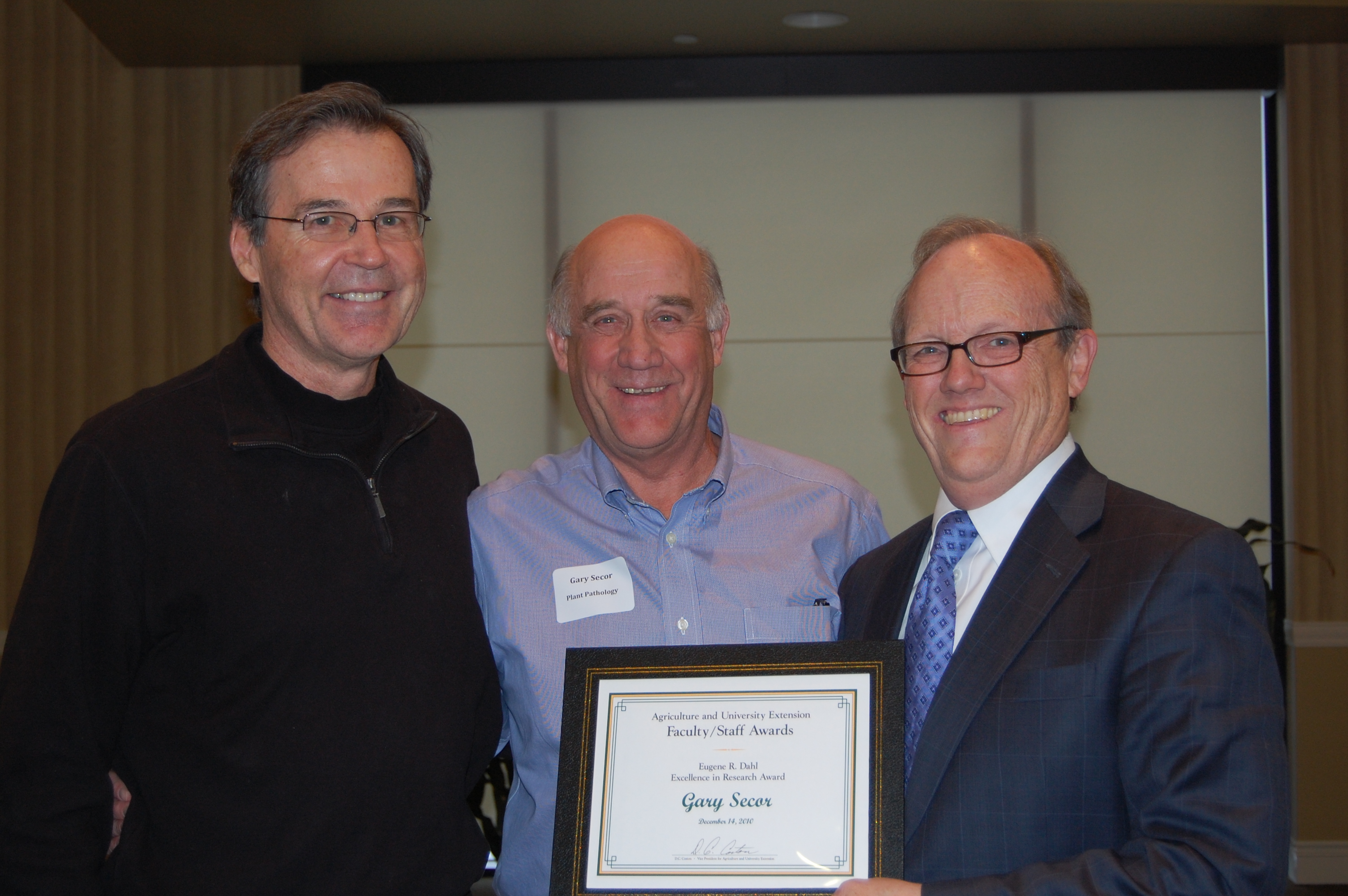 D.C. Coston, NDSU vice president for Agriculture and University Extension (right), presents the Eugene R. Dahl Excellence in Research Award to Gary Secor, a professor in the Plant Pathology Department. Howard Dahl, left, is a sponsor of the award.