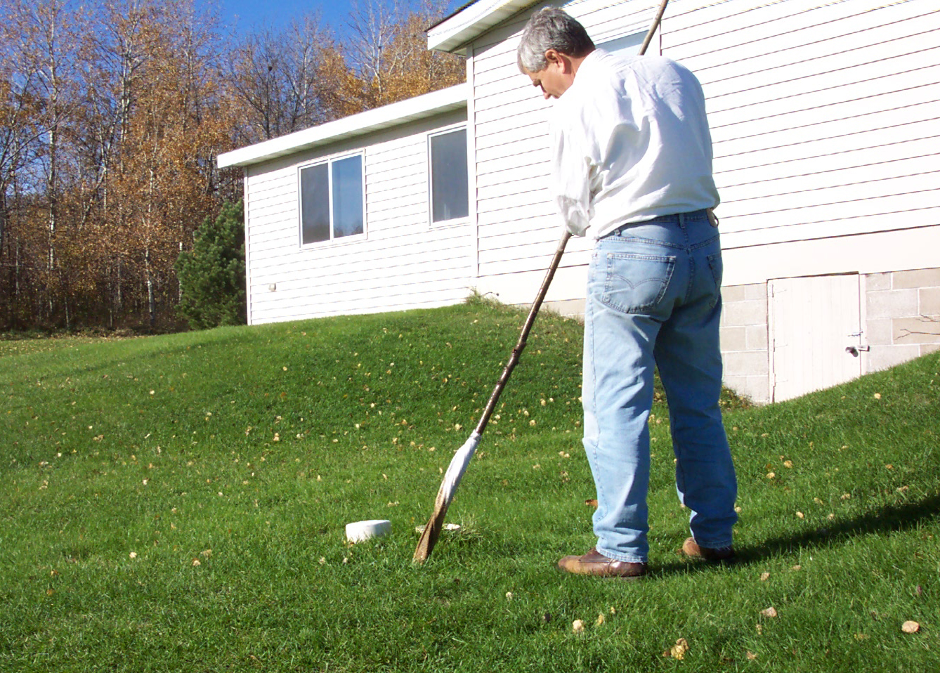 Tom Scherer, NDSU Extension agricultural engineer, demonstrates how to measure the depth of the sludge in a septic tank.