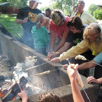 Youth learn how to cook food on sticks while attending camp at the 4-H Camp near Washburn.
