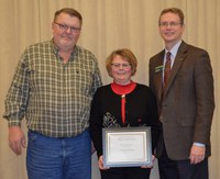 Cindy Olson, administrative assistant, Ramsey County Extension office, receives the Donald and Jo Anderson Staff Award from NDSU Extension Service Director Chris Boerboom, right, with Extension agent Bill Hodous, Ramsey County, at her side.