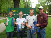 Oliver county team members (from left) Breanna Vosberg, Olivia Klein and Charlie Liffrig, accompanied by their coach, Extension agent Rick Schmidt, show off ribbons they recieved in the junior division of the 4-H dairy judging contest at NDSU.