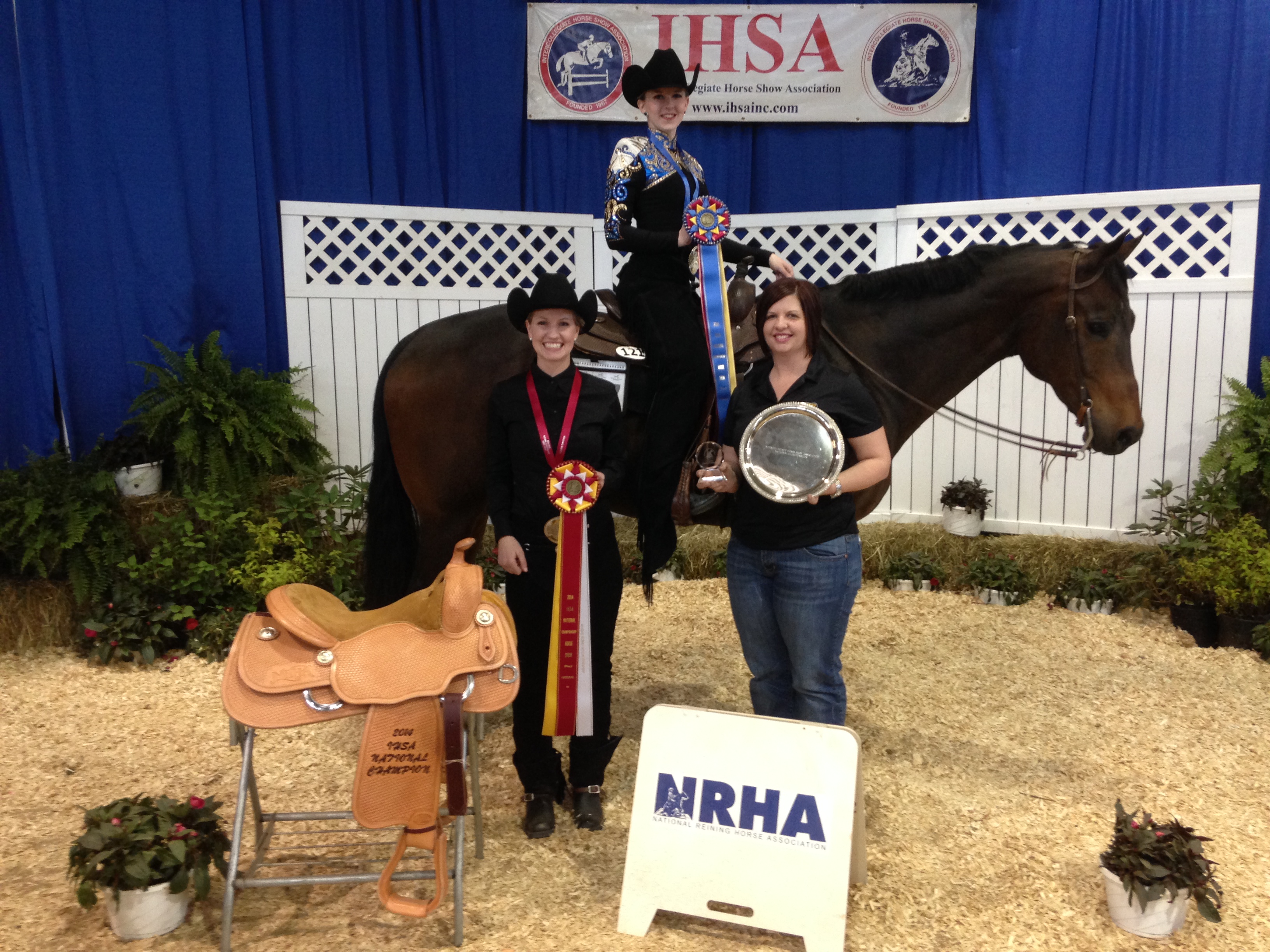 NDSU Western equestrian team members Hailey Aagard (on horseback) and Janna Rice (left), along with their coach, Tara Swanson, display the ribbons and other items they earned at the Intercollegiate Horse Show Association's National Championships in Harrisburg, Pa.