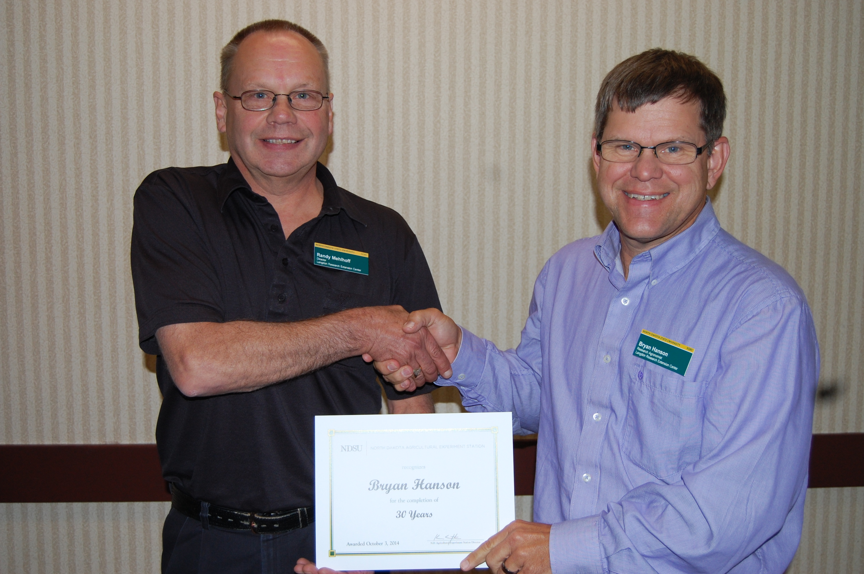 Randy Mehlhoff, Langdon Research Extension Center director (left), presents the award to Bryan Hanson.