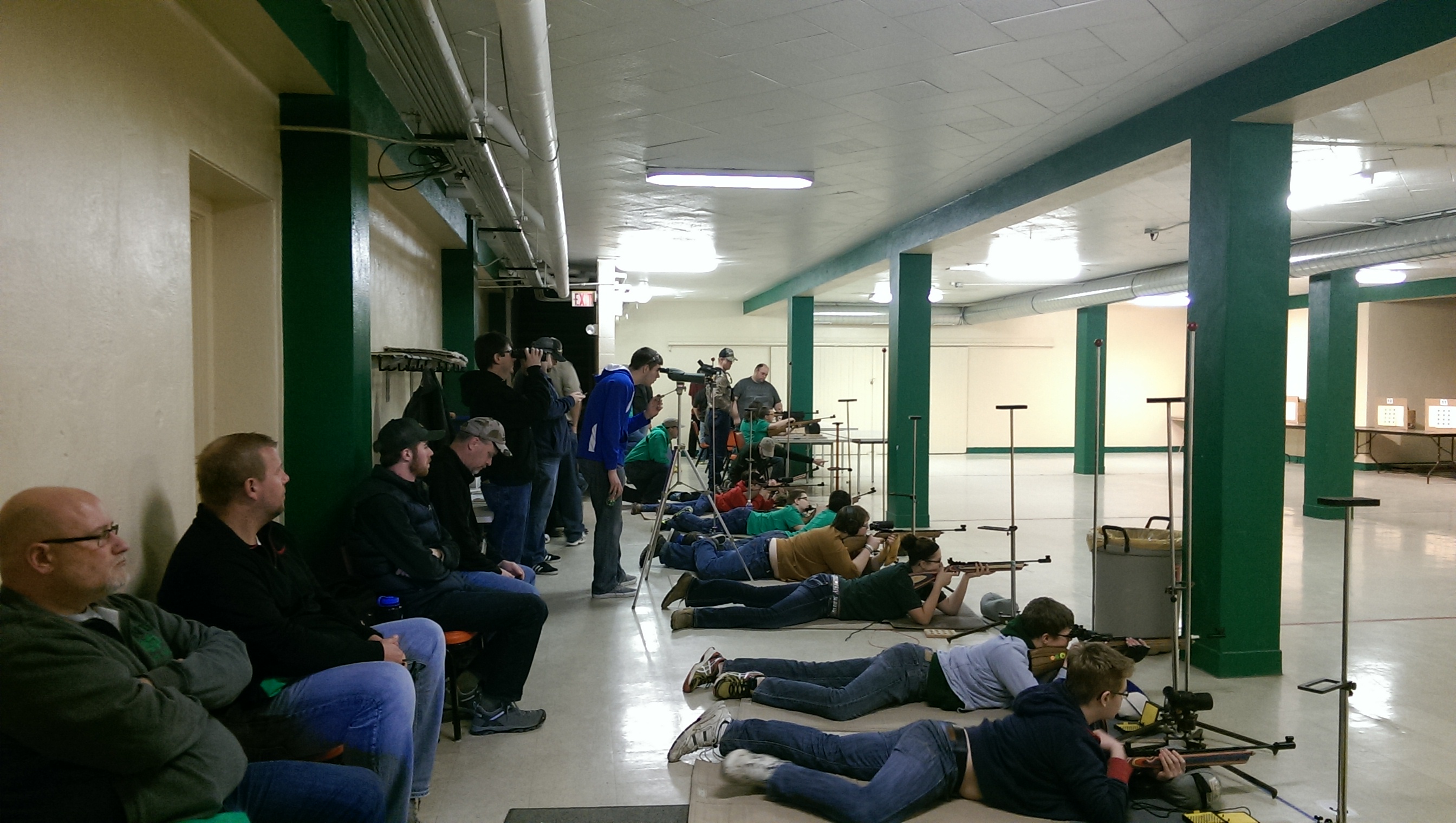 Youth compete in the senior division of the three-position event at the 2015 4-H state air rifle match in Devils Lake while parents watch. (NDSU photo)