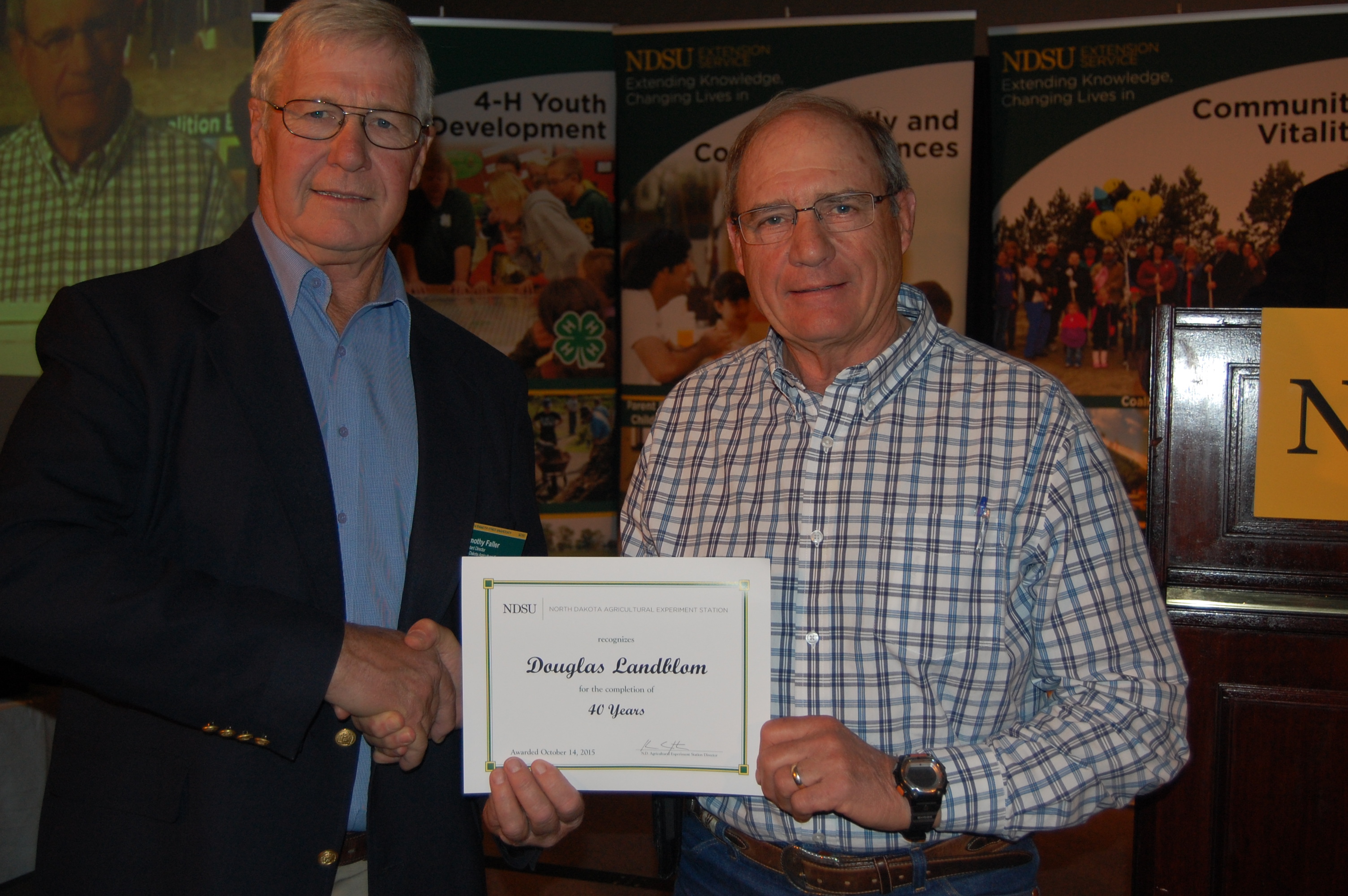 Douglas Landblom (left; award presented by Tim Faller, N.D. Agricultural Experiment Station assistant director, right)