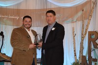 RLND Council chairman Mike O'Keeffe, right, presents Matt Dahlke, loan officer for Farm Credit Services of Mandan, with the RLND Champion Award that FCSM was honored with during the RLND Class VII graduation gala. (NDSU photo)
