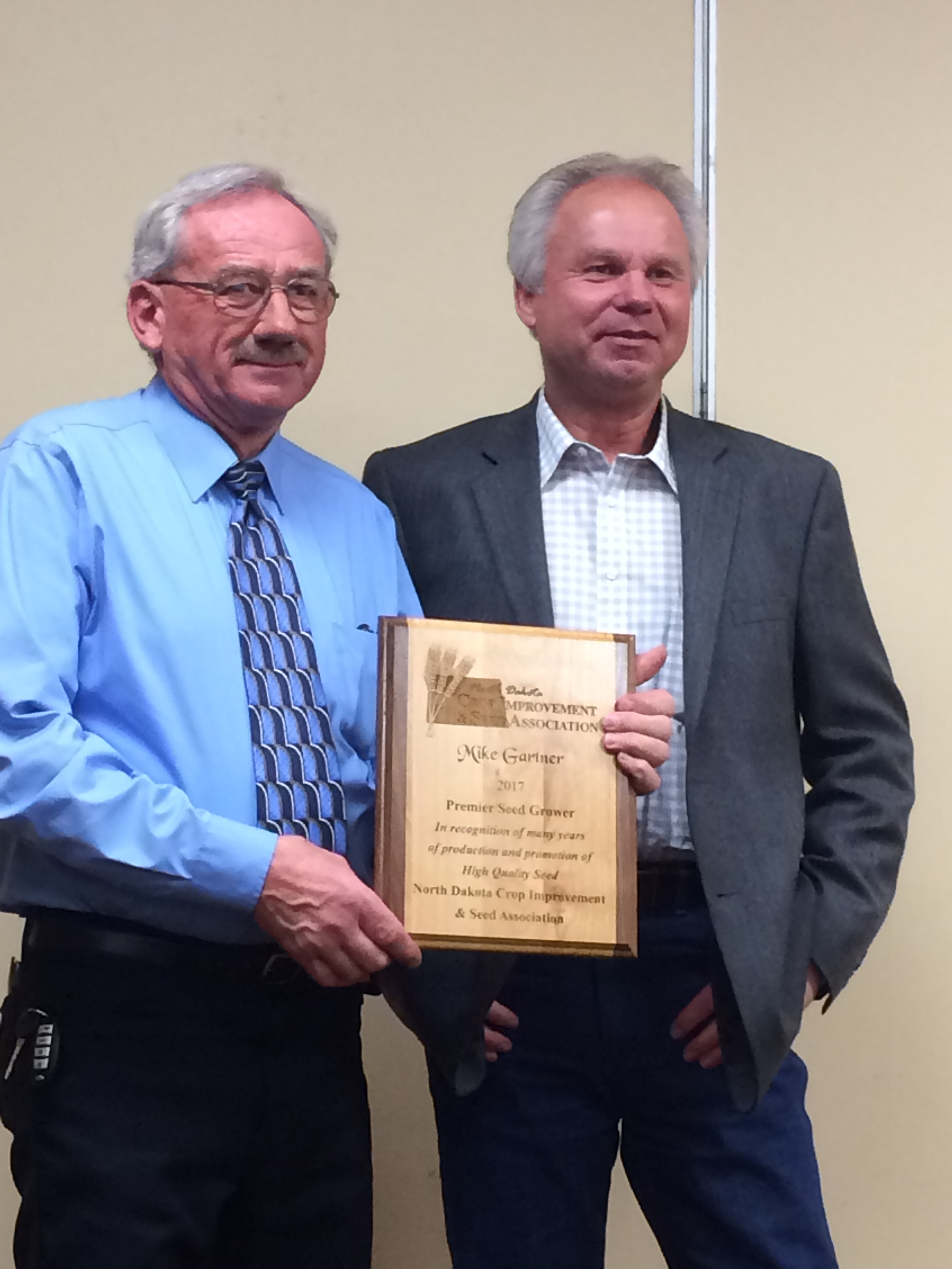 Mike Gartner (left), a procuder from Mandan, receives the Premier Seed Grower Award from Del Gates, president of the North Dakota Crop Improvement and Seed Association. (NDSU photo)