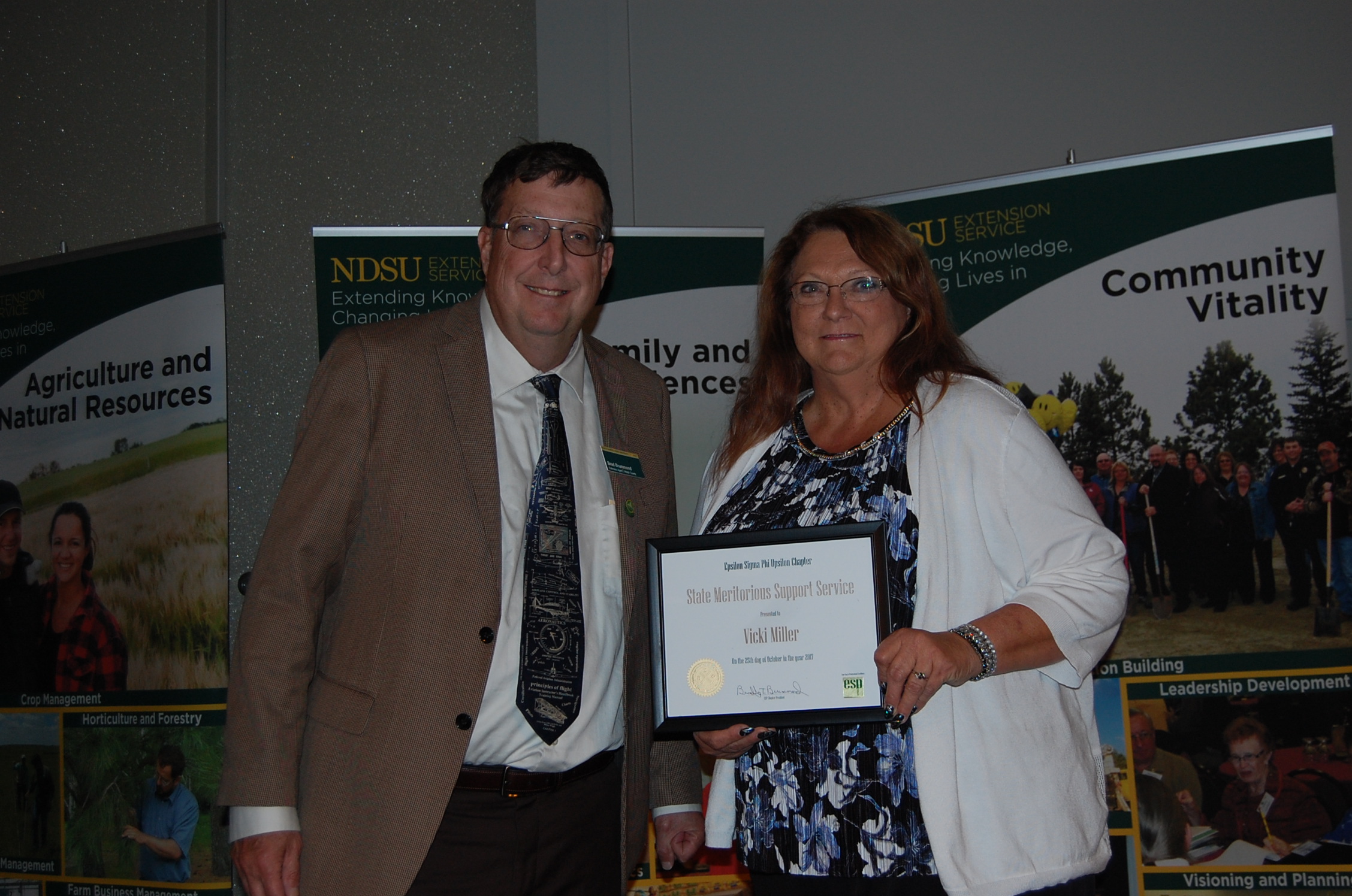 Vicki Miller receives the Meritorious Support Service Award from Brad Brummond, an agent in NDSU Extension's Walsh County office and president of the Upsilon Chapter of Epsilon Sigma Phi. (NDSU photo)