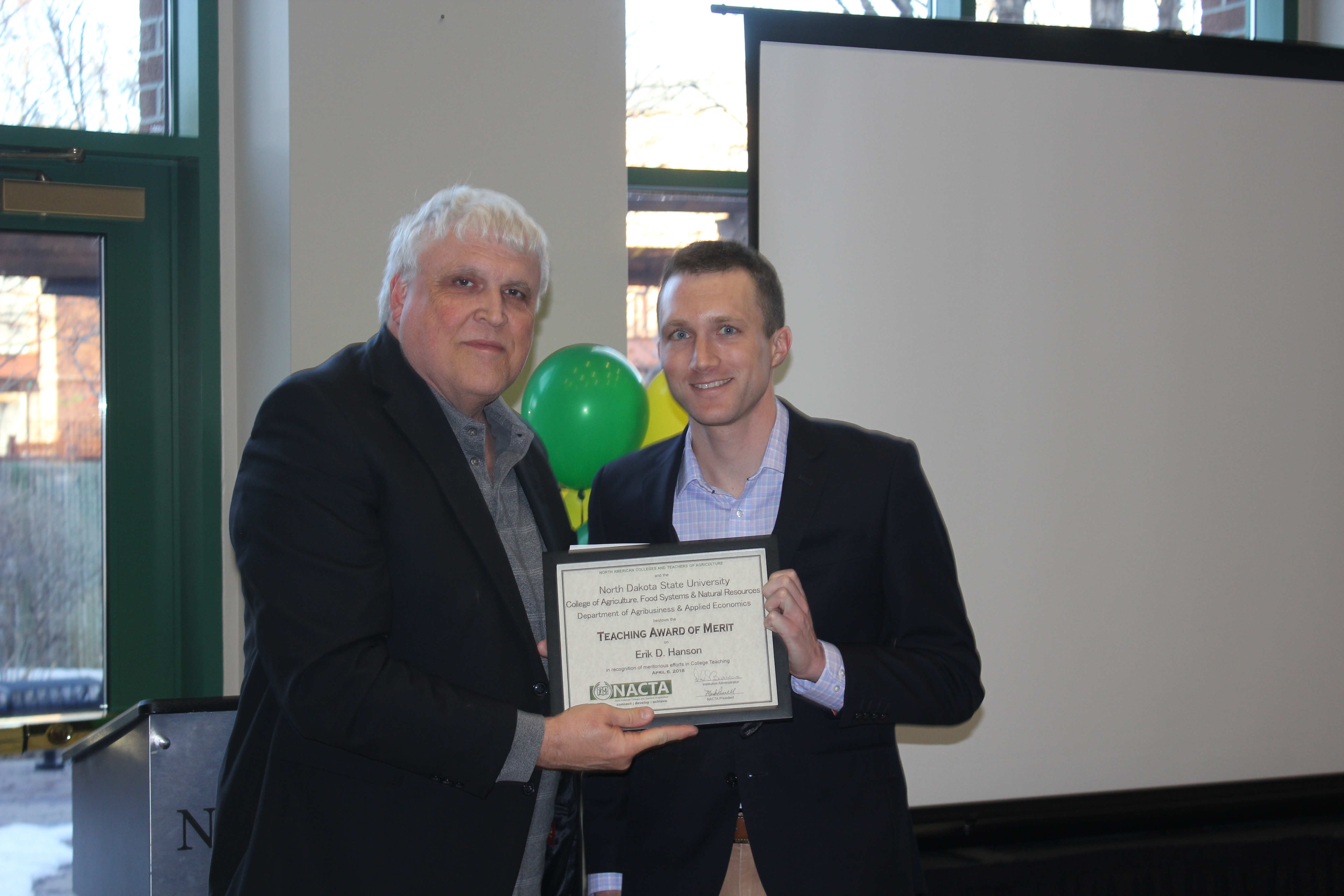 Erik Hanson, an assistant professor in NDSU's Agribusiness and Applied Economics Department (right), receives the North American Colleges and Teachers of Agriculture Teaching Award of Merit from David Buchanan, associate dean in NDSU's College of Agriculture, Food Systems, and Natural Resources. (NDSU photo)