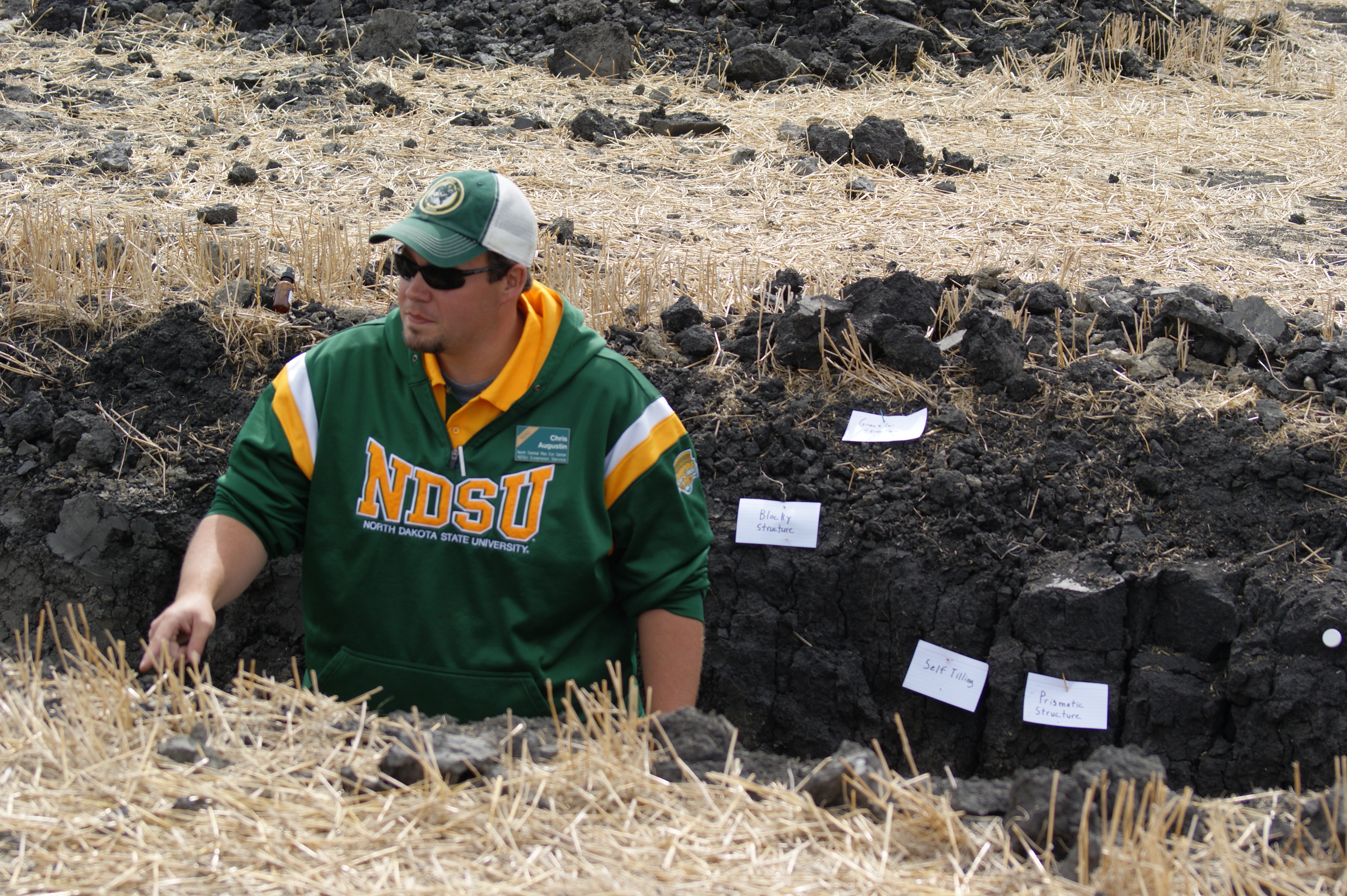 NDSU Extension soil health specialist Chris Augustin explains what is happening in the soil at this demonstration pit. (NDSU photo)