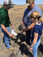 NDSU soil health technician Luke Ressler (left) helps a producer and his daughter estimate the soil health on their farm. (NDSU photo)