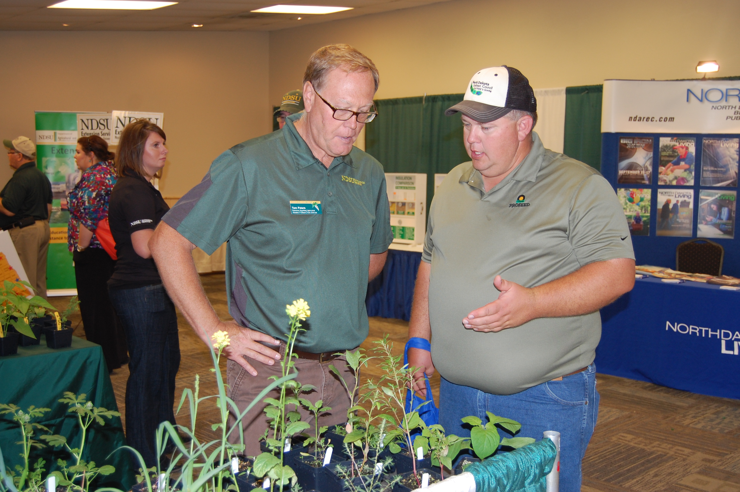 Tom Peters, NDSU Extension sugar beet agronomist (center), talks to a visitor about weeds during a Big Iron Farm Show. (NDSU photo)