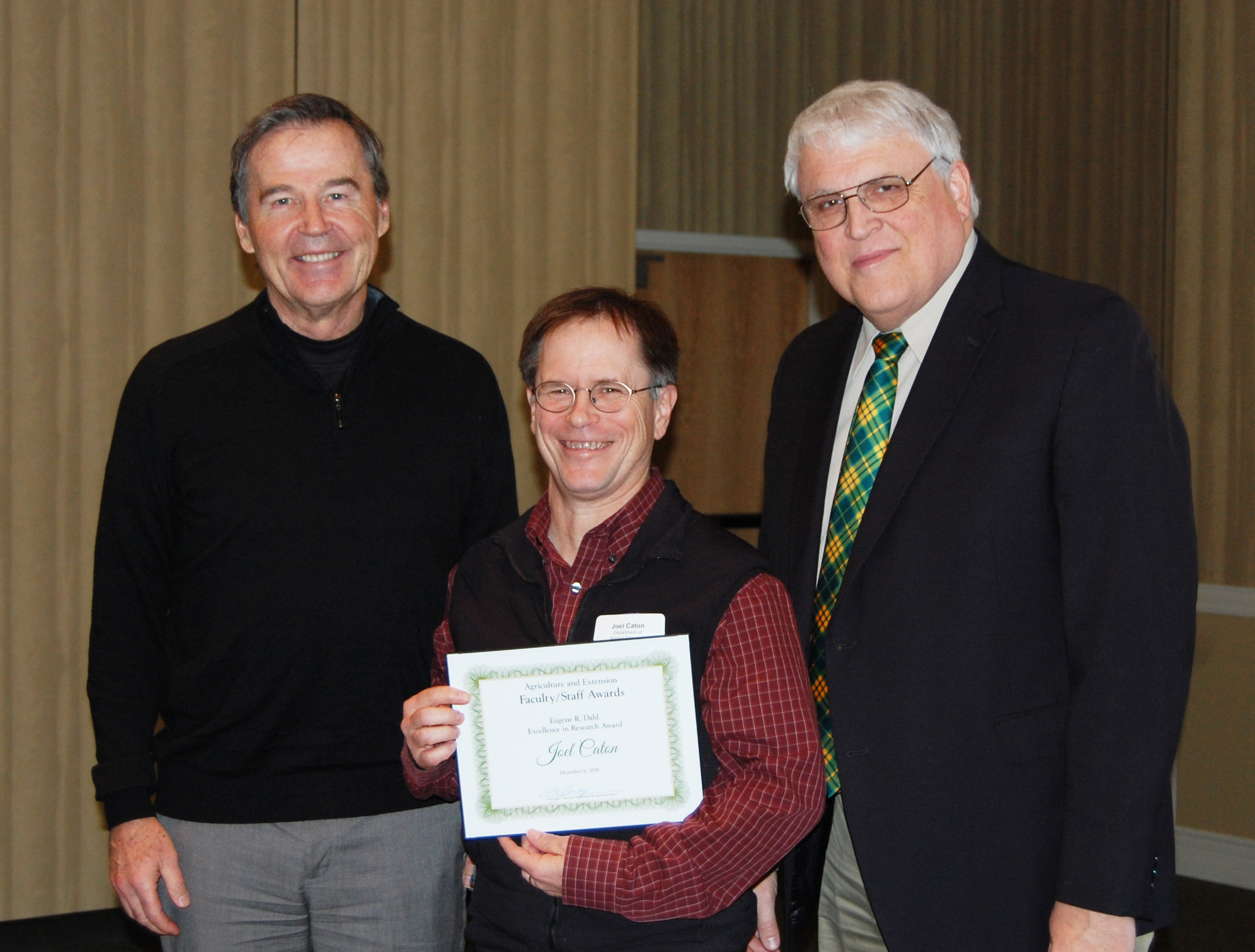 Joel Caton, center, receives the Eugene R. Dahl Excellence in Research Award from Howard Dahl, left, and David Buchanan, associate dean for academic programs. (NDSU photo)