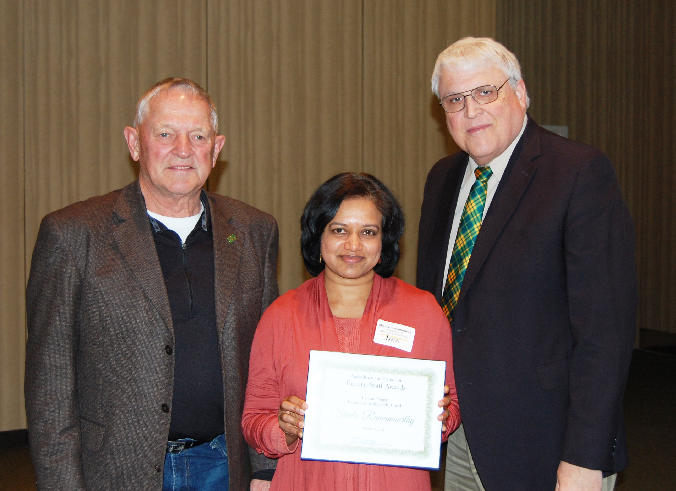 Sheela Ramamoorthy, center, receives the Larson/Yaggie Excellence in Research Award from Robert Yaggie, left, and David Buchanan, associate dean for academic programs. (NDSU photo)