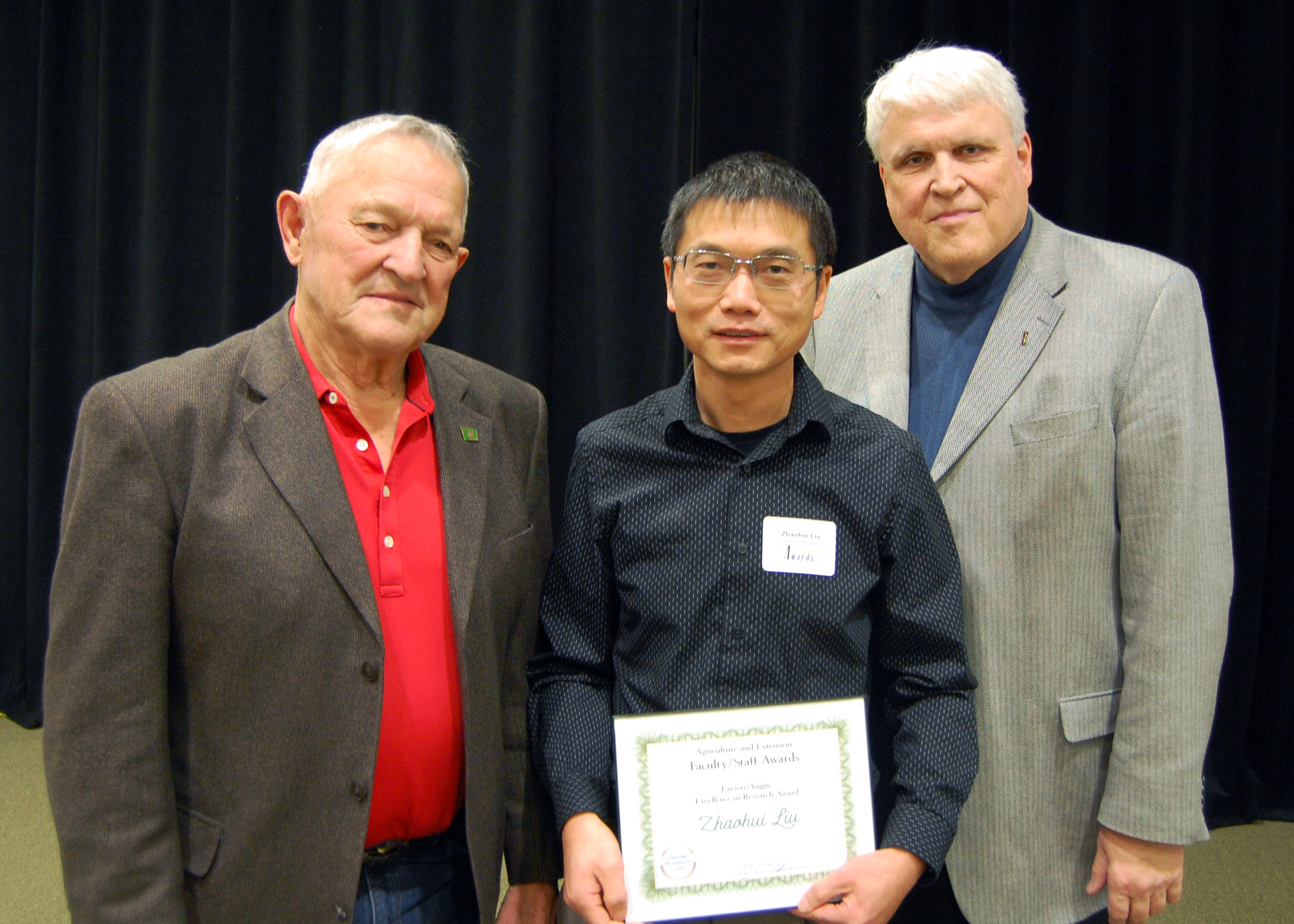 Zhaohui Liu, center, receives the Larson/Yaggie Excellence in Research Award from Robert Yaggie, left, and David Buchanan, associate dean for academic programs. (NDSU photo)