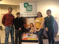 North Dakota 4-H'ers who attended the 4-H Youth AgriScience Summit stand in front of a poster promoting the summit. Pictured are (from left) Mitch Stuber, Noah Helgoe and Haley Cowan, and chaperone Sarah McNaughton. (NDSU photo)