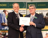 NDSU vice president Greg Lardy (left) presents Blaine Schatz, assistant director of the North Dakota Agricultural Experiment Station, with his award for 45 years of service. (NDSU photo)