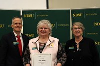 Linda Schuster (center) is recognized for 10 years of service to NDSU Extension. Also pictured are Greg Lardy, vice president for NDSU Agriculture, and Lynette Flage, associate director for NDSU Extension. (NDSU photo)