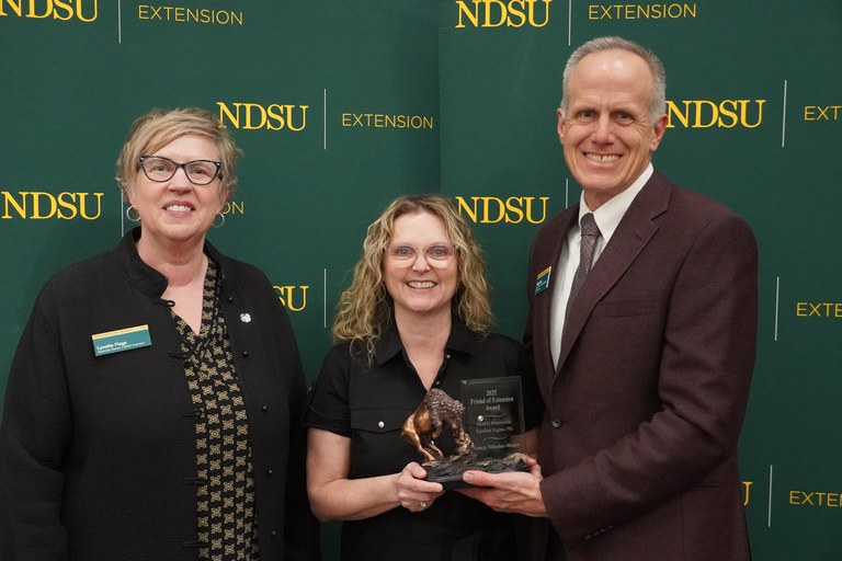Nancy Nikolas-Maier (center), director of Adult and Aging Services at the North Dakota Department of Health & Human Services, is honored with the 2025 Friend of Extension award by Lynette Flage (left), NDSU Extension associate director, and Greg Lardy (right), Joe and Norma Peltier Vice President for Agriculture at NDSU. (NDSU photo)