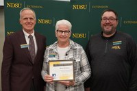 Marie Hvidsten (center), program coordinator for NDSU Extension’s leadership and civic engagement, is honored with the North Dakota Extension Association of Family and Consumer Sciences award by Greg Lardy (left), Joe and Norma Peltier Vice President for Agriculture at NDSU, and Dustin Hammond (right), vice president of public affairs for NDEAFCS. (NDSU photo)
