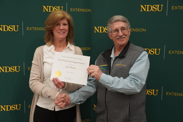 Jane Hayen (left), administrative assistant in Cavalier County, is honored with the Epsilon Sigma Phi State Meritorious Support Staff Award by Dan Folske (right), NDSU Extension agriculture and natural resources agent in Burke County. (NDSU photo)