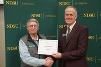 Dan Folske (left), NDSU Extension agent for Burke County, is honored for 35 years of service by Greg Lardy (right), Joe and Norma Peltier Vice President for Agriculture at NDSU. (NDSU photo)