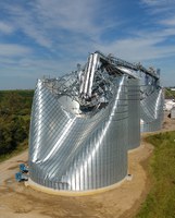 Wind load on a bin wall pushes in on the windward side of the bin while it pulls out away in the remaining directions, which has bent this Iowa bin out of shape. (Photo by the National Weather Service)