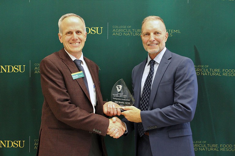 Greg Lardy, Joe and Norma Peltier Vice-President for Agriculture at NDSU (left), presents Michael Uetz (right) the 2025 NDSU CAFSNR Distinguished Alumni Award. (NDSU photo)