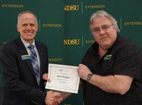 Ron Haugen (right), NDSU Extension farm management specialist, is honored for 35 years of service by Greg Lardy (left), Joe and Norma Peltier Vice President for Agriculture at NDSU. (NDSU photo)