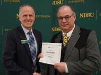 Kurt Froelich (right), NDSU Extension agriculture and natural resources agent in Stark/Billings County, is honored for 40 years of service by Greg Lardy (left), Joe and Norma Peltier Vice President for Agriculture at NDSU. (NDSU photo)