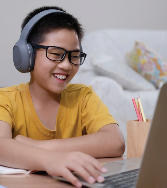 young boy with headphones working on a laptop