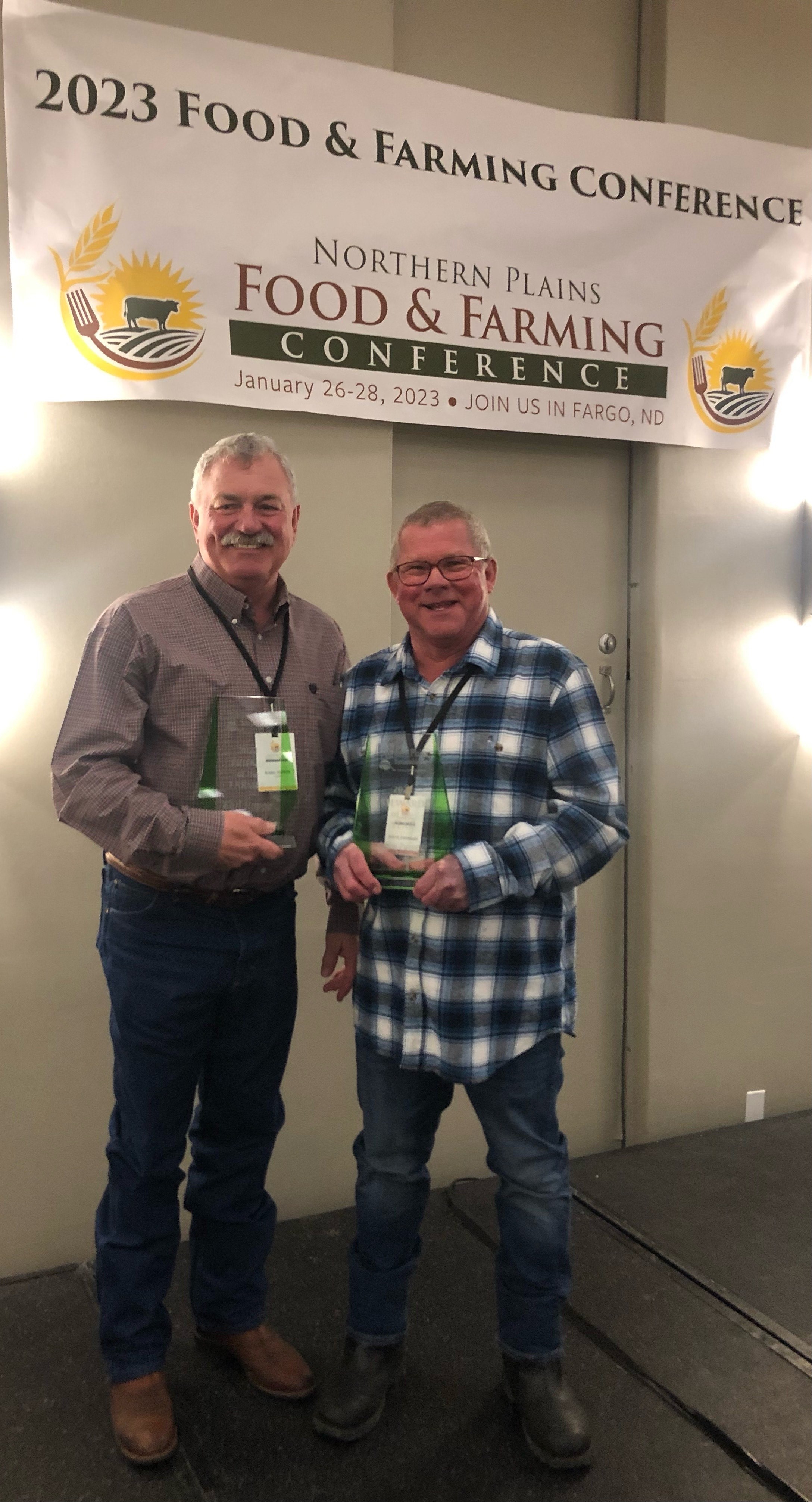 NDSU Carrington Research Extension Center’s Karl Hoppe and Steve Zwinger (retired) receive awards at the Northern Plains Food and Farming Conference. (NDSU photo)