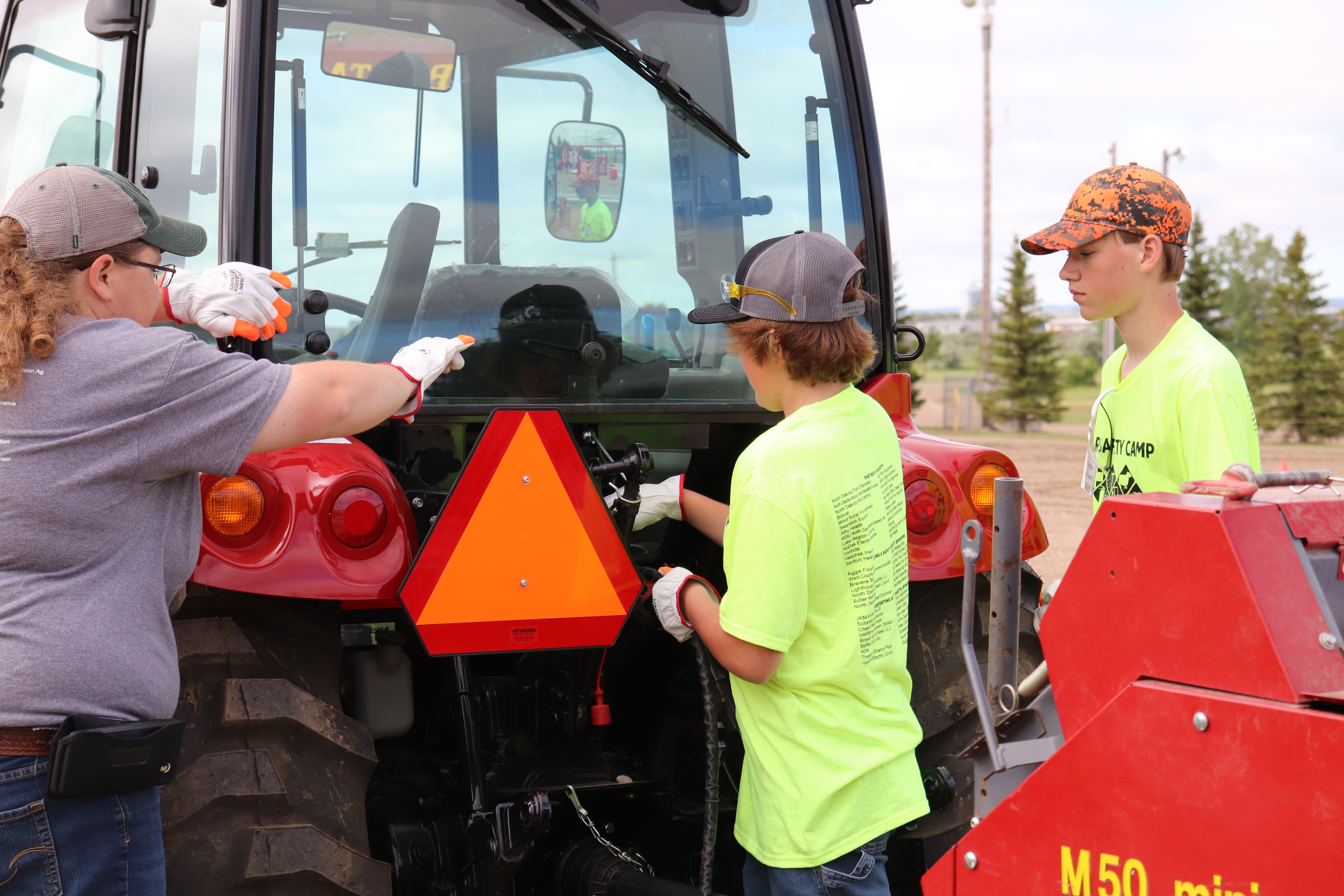 Teen farm safety camp participants demonstrate how to properly connect hydraulic hoses and power take-off shafts of farm equipment to a tractor. (NDSU photo)