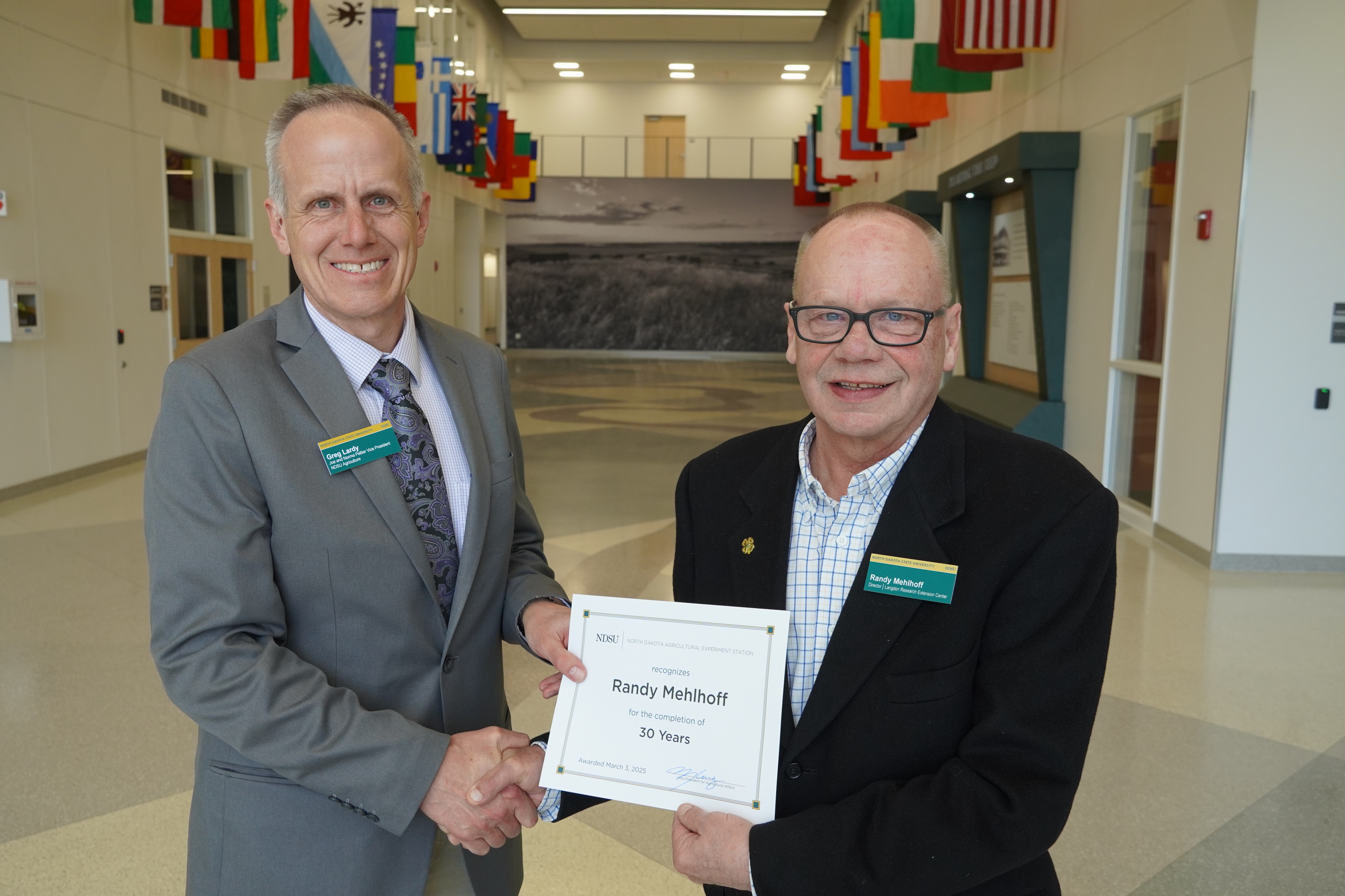Randy Mehlhoff (30 years) receives congratulations from Greg Lardy. (NDSU photo)